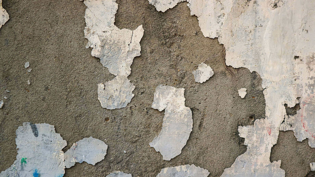 Peeling paint and damaged concrete surface showing signs of deterioration and neglect.