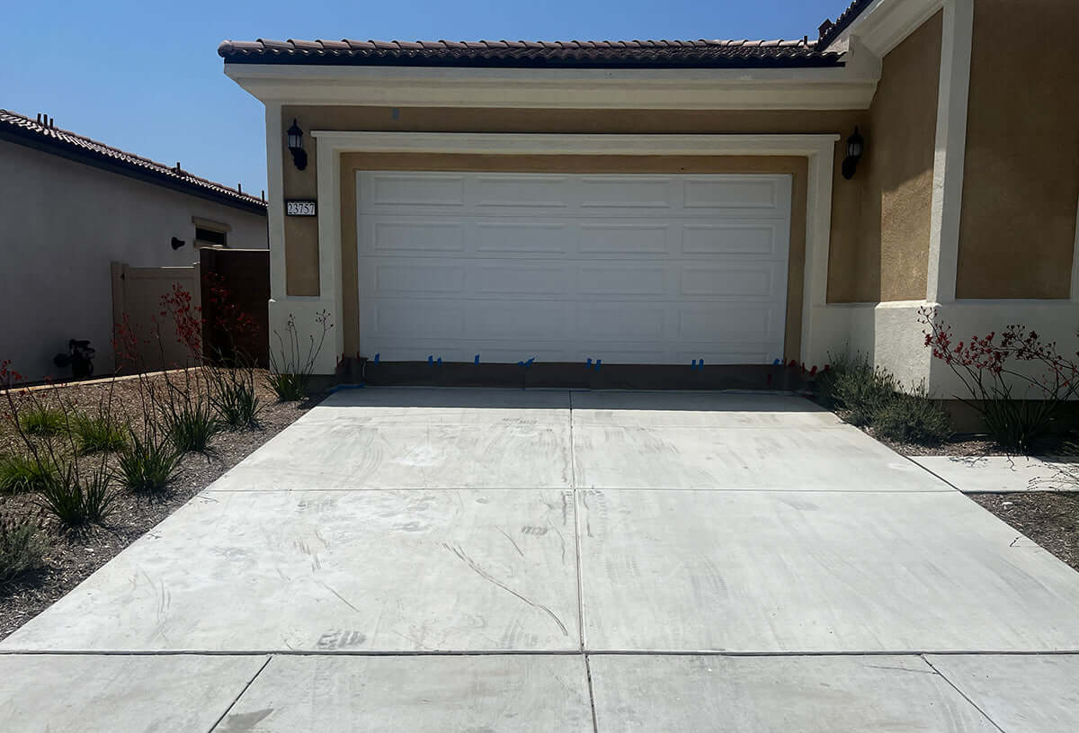 Freshly resurfaced concrete driveway by Like Nu Concrete Resurfacing in front of a modern residential garage.
