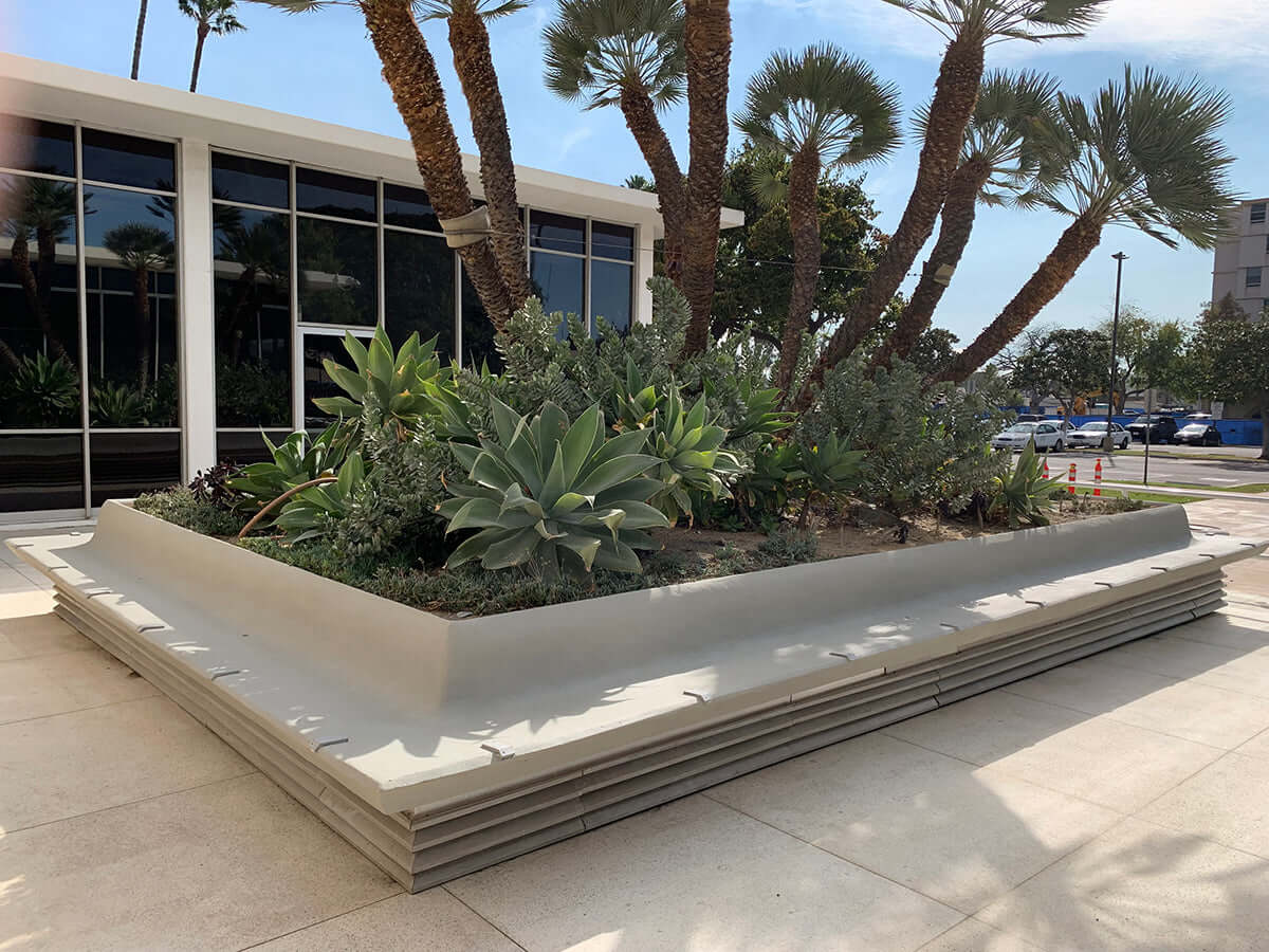 Modern concrete planter with succulents and palm trees restored using Like Nu Concrete Restoration Kit in an urban setting.