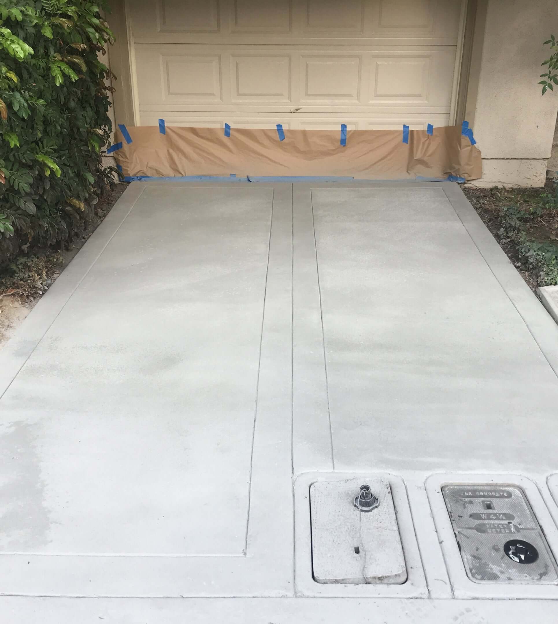 Freshly restored driveway using Like Nu Concrete Restoration Kit, with garage door protected by paper and tape.