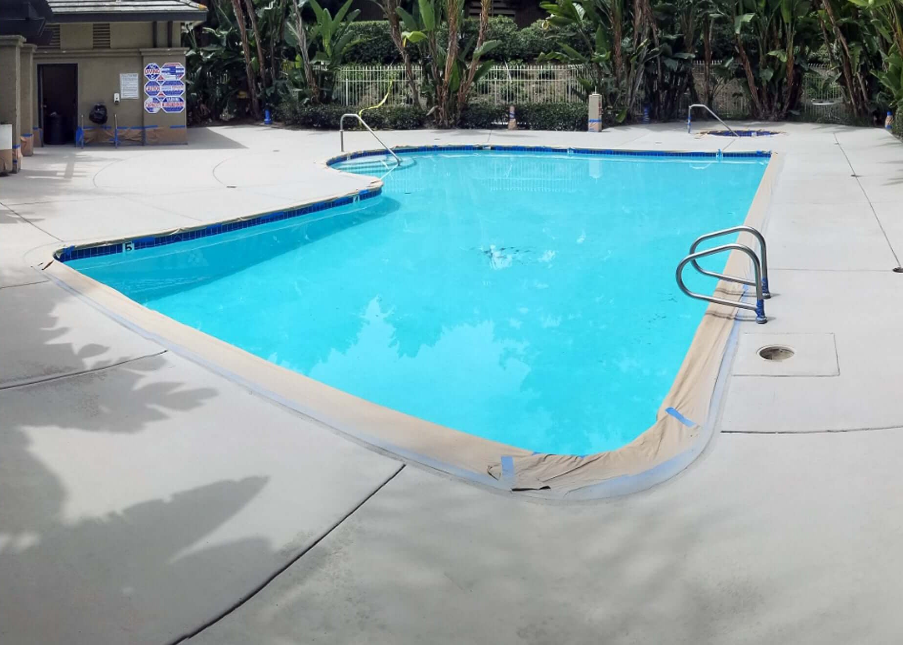 Newly Restored Concrete Pool Deck Surrounding a Clean Swimming Pool