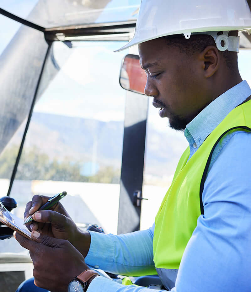 Construction worker in hard hat and safety vest writing on clipboard for Like Nu Commercial Services.