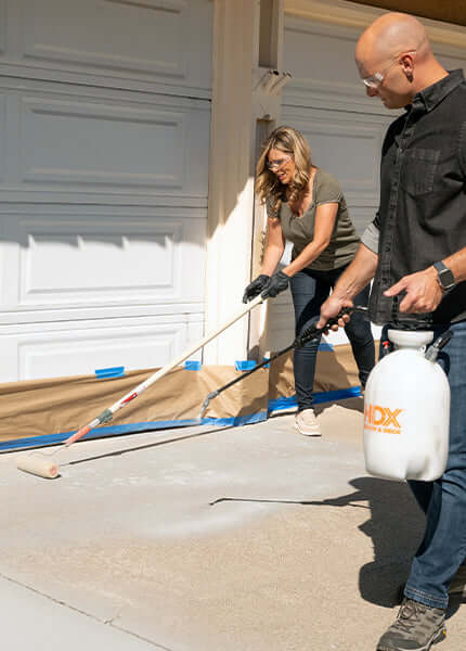 Couple applying Like-Nu Concrete mix to their driveway, showing effective concrete restoration techniques.