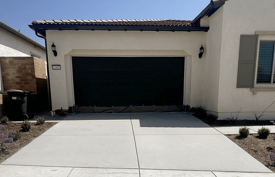 Modern suburban house with a clean white concrete garage door and neatly landscaped driveway