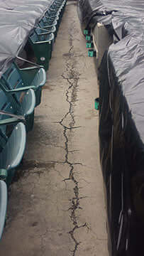 Cracked concrete pathway between stadium seats requiring repair by Like Nu Commercial Services.
