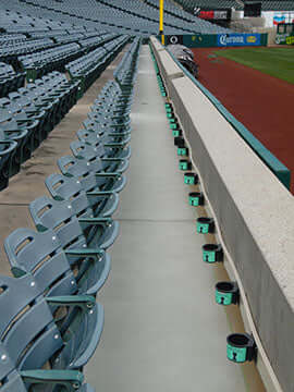 Restored concrete walkway in a commercial stadium with rows of seats on one side and a clear view of the baseball field.